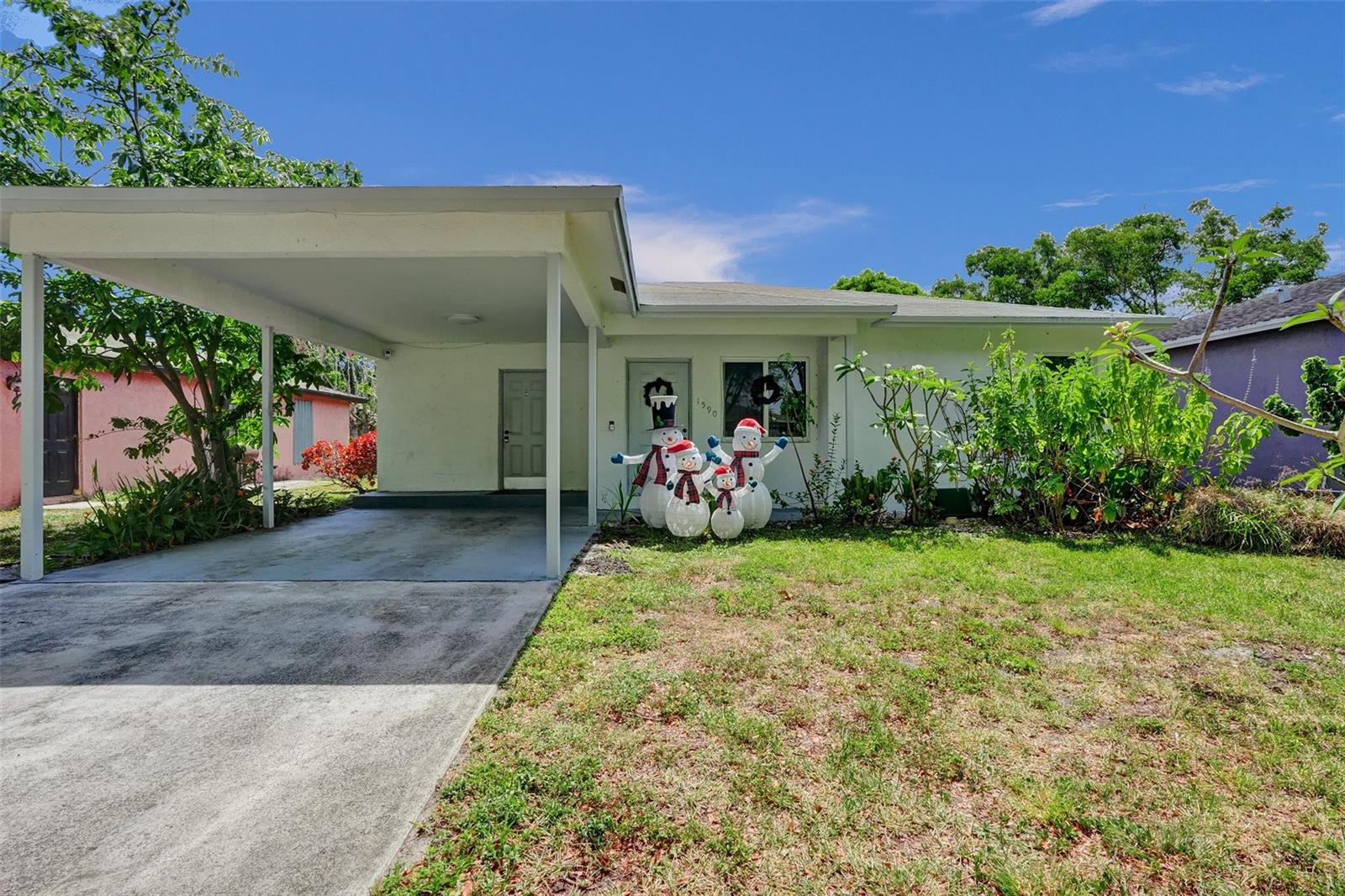 A single-story house with a carport, a front lawn, and snowman decorations by the entrance — 1590 NW 7th Lane, Pompano Beach FL 33060, POMPANO BEACH, FL