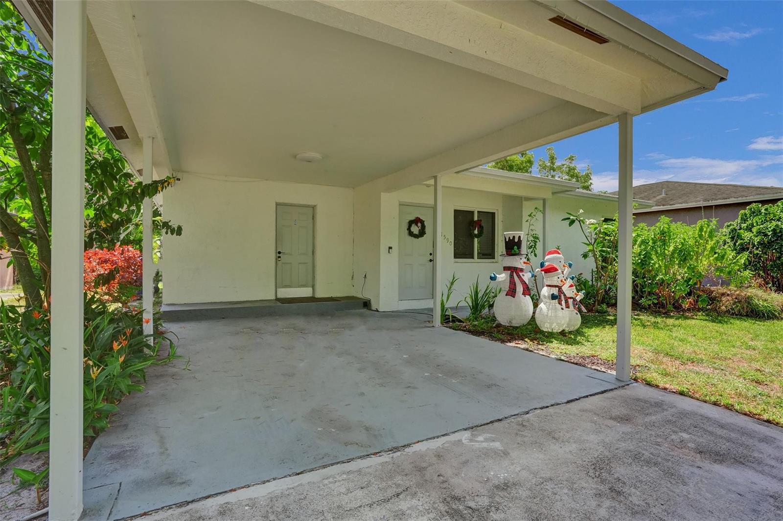 A concrete carport leads to the front entrance of a house decorated with snowman figures — 1590 NW 7th Lane, Pompano Beach FL 33060, POMPANO BEACH, FL
