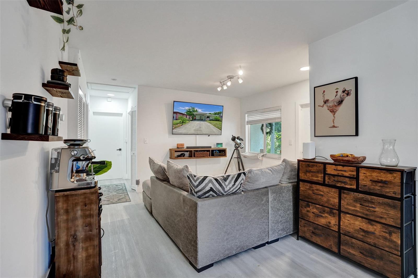 A living room features a sectional sofa, wall-mounted television, coffee station, and wooden dresser — 1590 NW 7th Lane, Pompano Beach FL 33060, POMPANO BEACH, FL