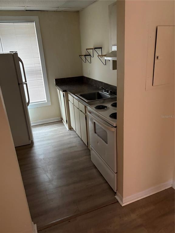 A small kitchen features light wood-look flooring, white appliances, and a stainless steel sink — 111 S NEWPORT AVENUE UNIT 6, TAMPA, FL