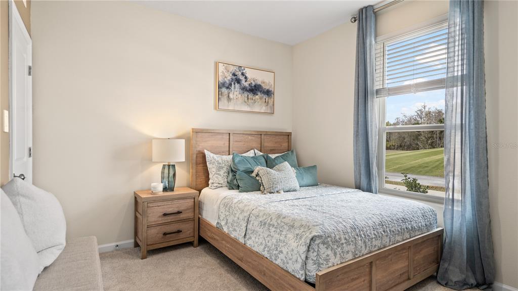 A bedroom features a wooden bed frame, a matching nightstand, and a window with curtains — 886 TUNDRA LOOP, GROVELAND, FL