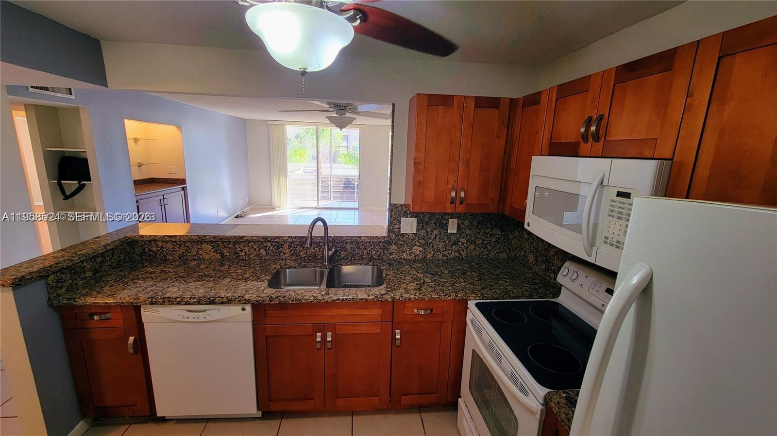 A kitchen features wood cabinets, granite countertops, a white dishwasher, and a white stove — 406 NW 68th Ave # 304, Plantation FL 33317, PLANTATION, FL