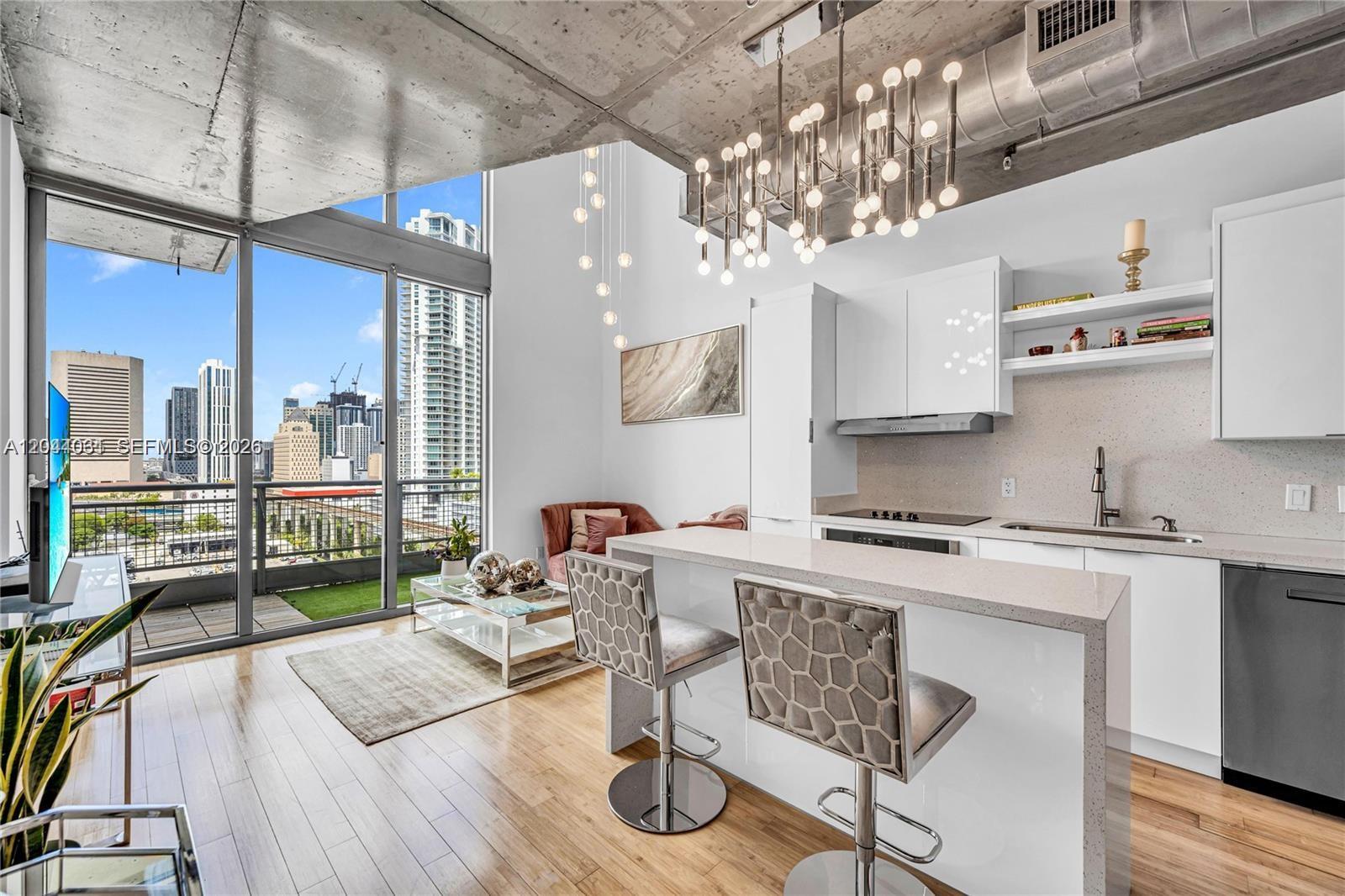 A modern apartment kitchen and living area features high ceilings, a balcony, and city views — 690 SW 1st Ct # 1709, Miami FL 33130, MIAMI, FL