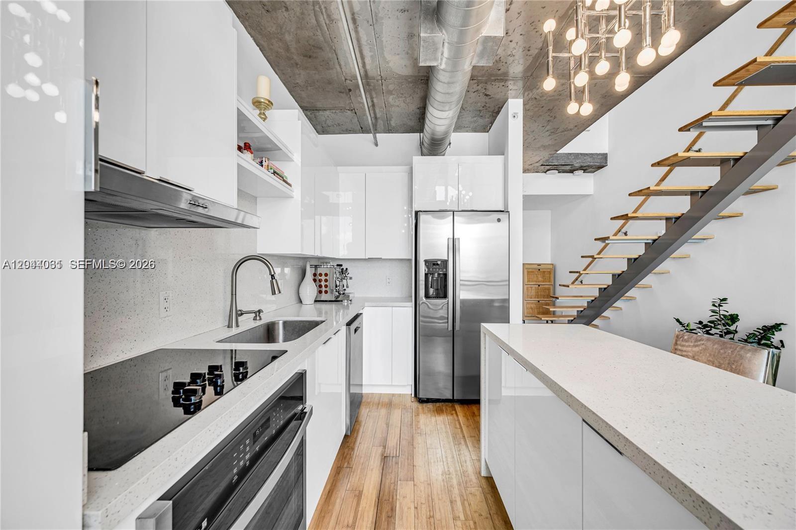A modern kitchen features white cabinetry, stainless steel appliances, and an open staircase — 690 SW 1st Ct # 1709, Miami FL 33130, MIAMI, FL