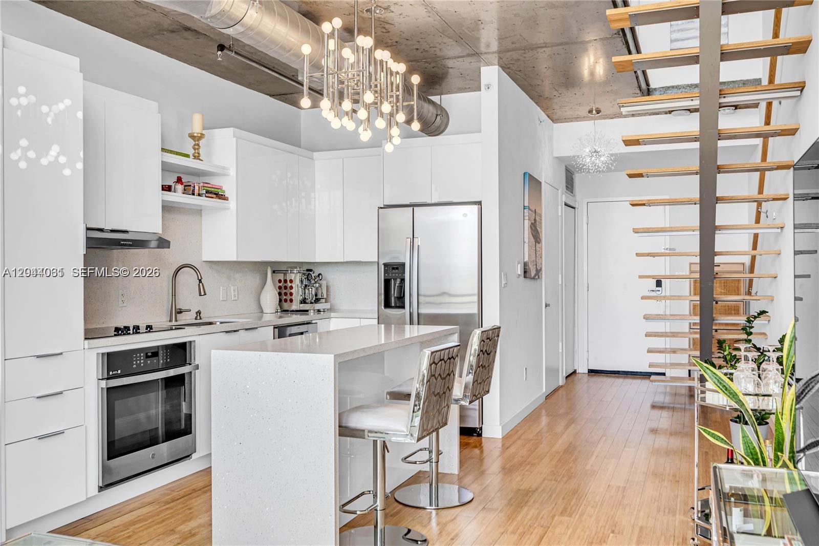 A modern kitchen features white cabinetry, a quartz island, and an exposed concrete ceiling — 690 SW 1st Ct # 1709, Miami FL 33130, MIAMI, FL