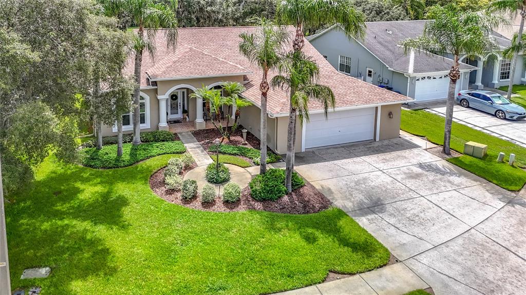 An aerial view of a single-story house with a tan exterior, shingled roof, and landscaping — 13540 PLANTATION LAKE CIRCLE, HUDSON, FL