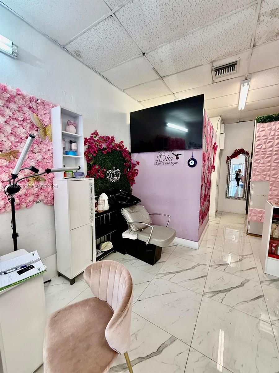 A salon interior features a shampoo station, pink floral wall, and light-colored marble flooring — 1569 W OKEECHOBEE RD HIALEAH, Hialeah FL 33010, HIALEAH, FL