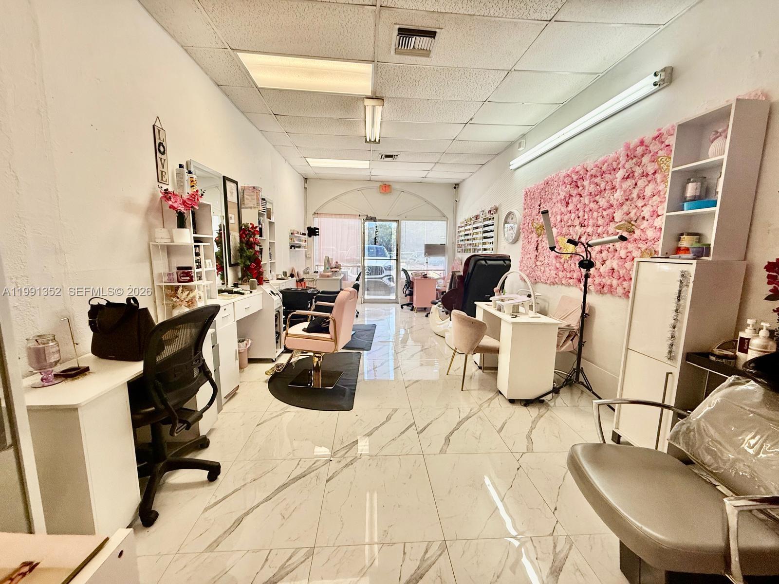 A bright salon interior features white marble-look tile flooring and a floral accent wall — 1569 W OKEECHOBEE RD HIALEAH, Hialeah FL 33010, HIALEAH, FL