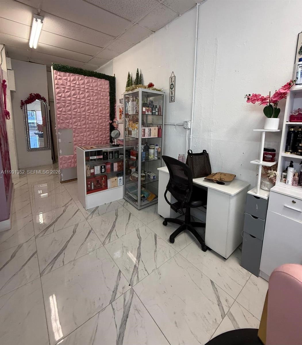 A small salon interior features white marble-look tile flooring, a pink textured wall, and shelving — 1569 W OKEECHOBEE RD HIALEAH, Hialeah FL 33010, HIALEAH, FL