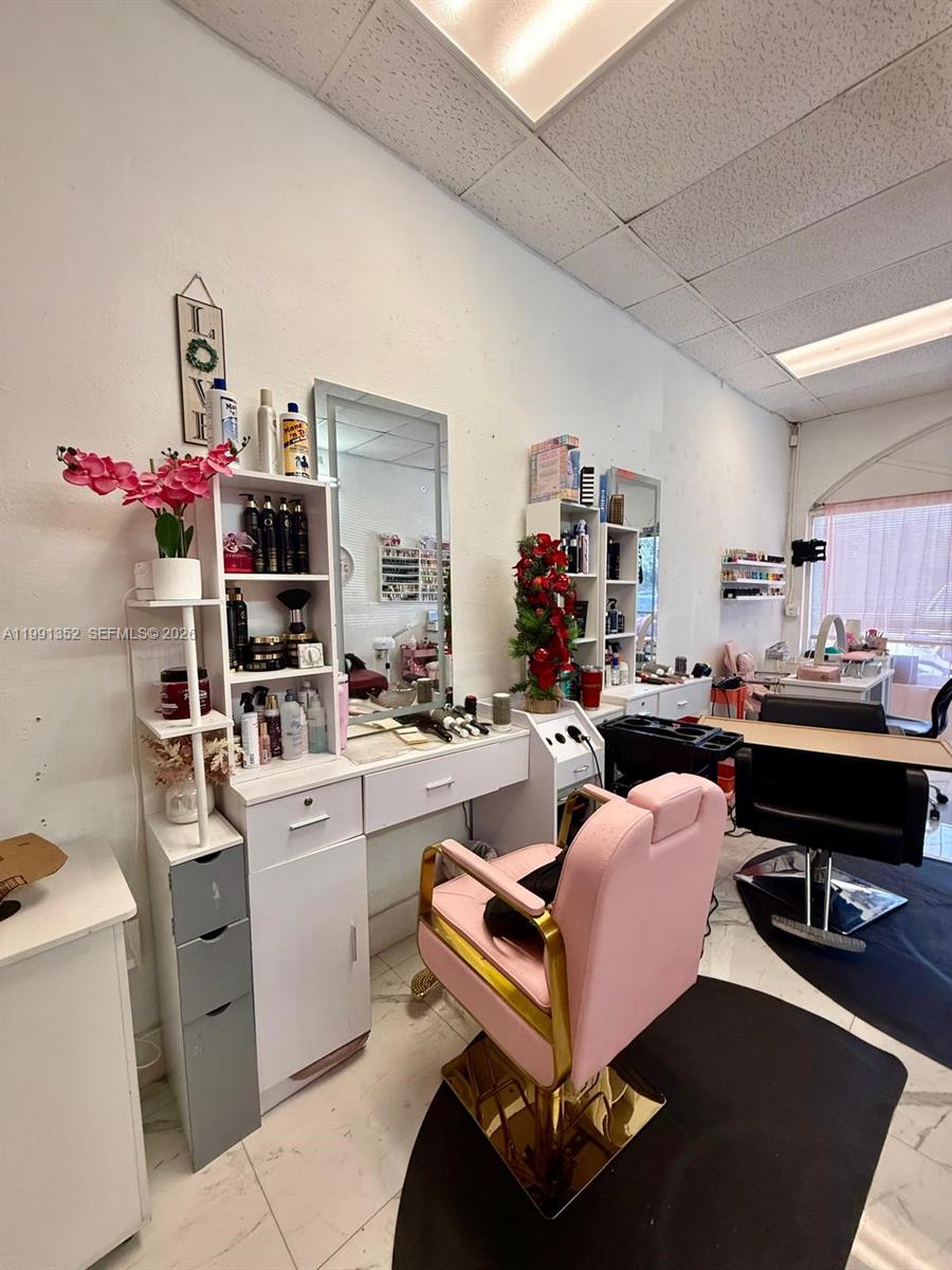 A salon station features a pink chair, white vanity, mirror, and shelves with hair products — 1569 W OKEECHOBEE RD HIALEAH, Hialeah FL 33010, HIALEAH, FL