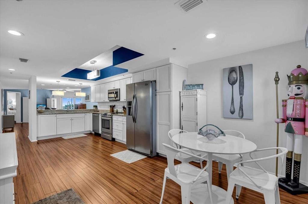 A kitchen with white cabinets, stainless steel appliances, and a small dining area with chairs — 5621 GULF OF MEXICO DRIVE UNIT 102, LONGBOAT KEY, FL
