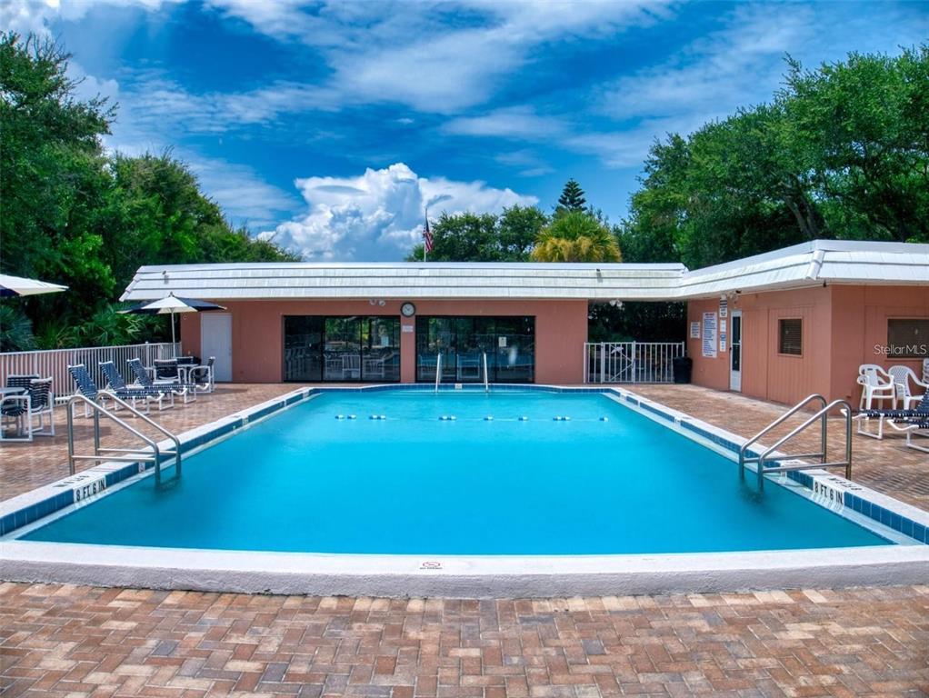 A rectangular swimming pool sits in front of a single-story building with a patio — 4150 S ATLANTIC AVENUE UNIT 113D, NEW SMYRNA BEACH, FL