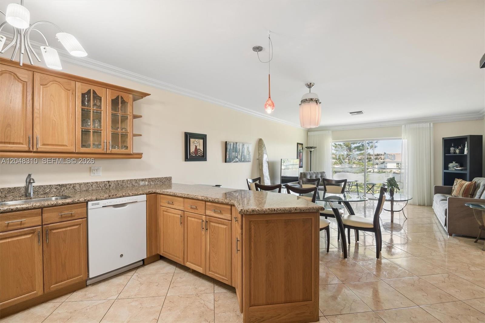 An open-concept kitchen and living area features light wood cabinets, granite countertops, and tile flooring — 1000 Hillcrest Ct # 303, Hollywood FL 33021, HOLLYWOOD, FL