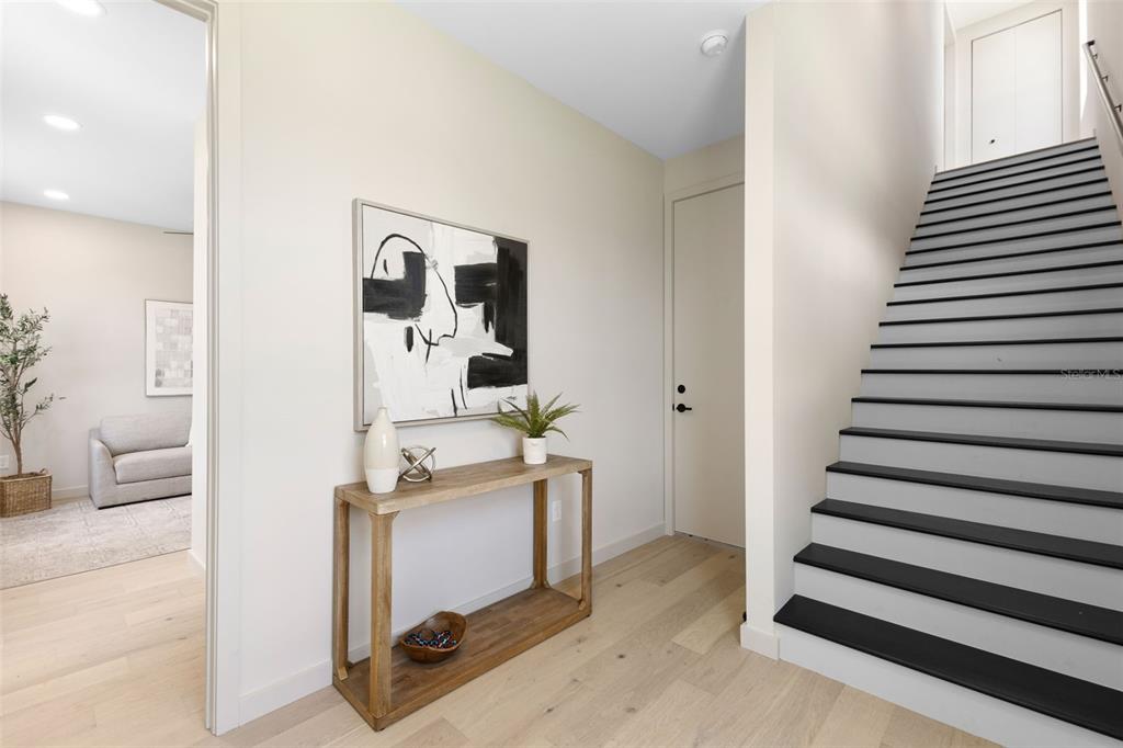 A modern entryway features light wood flooring, a console table, abstract art, and a staircase — 2205 16TH STREET N, ST PETERSBURG, FL