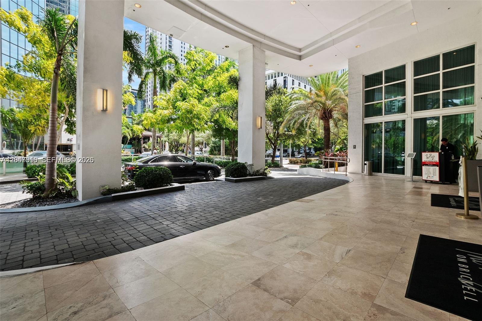 A covered outdoor entrance area features stone tile flooring, large white columns, and palm trees — 951 Brickell Ave # 3207, Miami FL 33131, MIAMI, FL