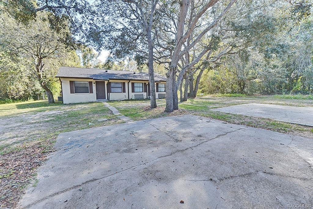 A single-story house with a concrete driveway and large trees in the front yard — 512 LONG AVENUE, INVERNESS, FL