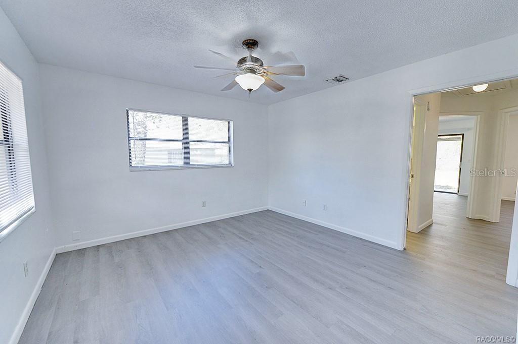 A bedroom with white walls, light gray wood-look flooring, and a ceiling fan — 512 LONG AVENUE, INVERNESS, FL