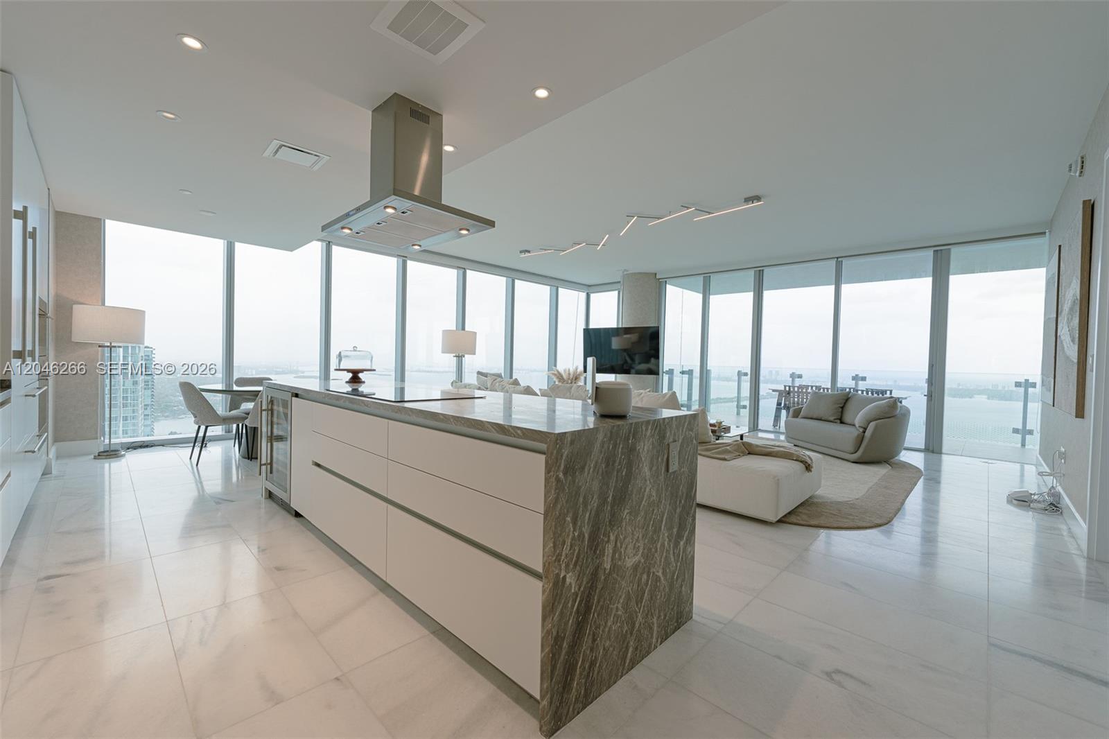 A modern kitchen island with stone waterfall edges sits in an open-concept living space — 700 NE 26th Ter # 4901, Miami FL 33137, MIAMI, FL