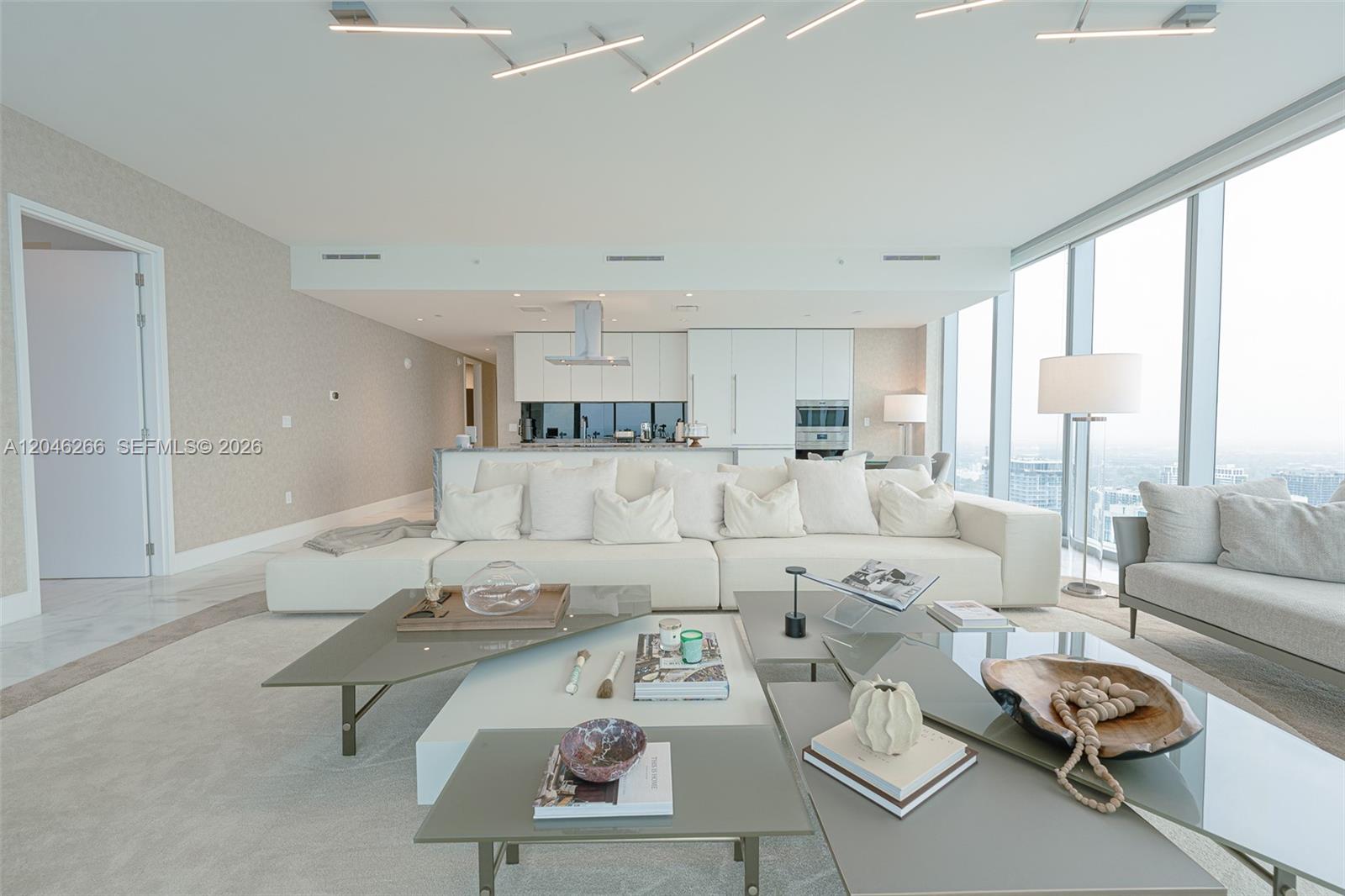 A modern open-concept living room features a large white sectional sofa and tiered coffee tables — 700 NE 26th Ter # 4901, Miami FL 33137, MIAMI, FL
