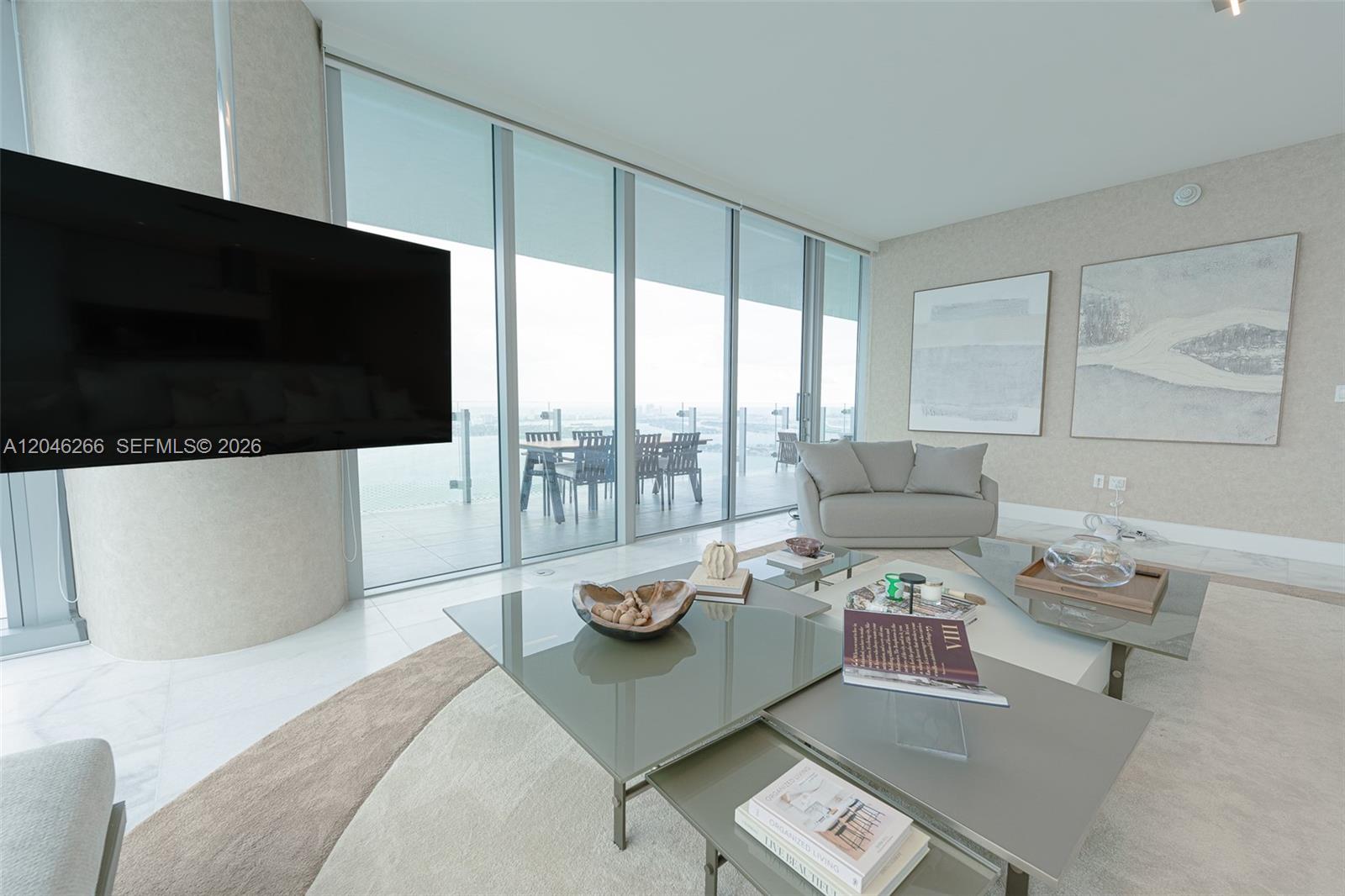 A modern living room features floor-to-ceiling windows, a large television, and layered glass coffee tables — 700 NE 26th Ter # 4901, Miami FL 33137, MIAMI, FL