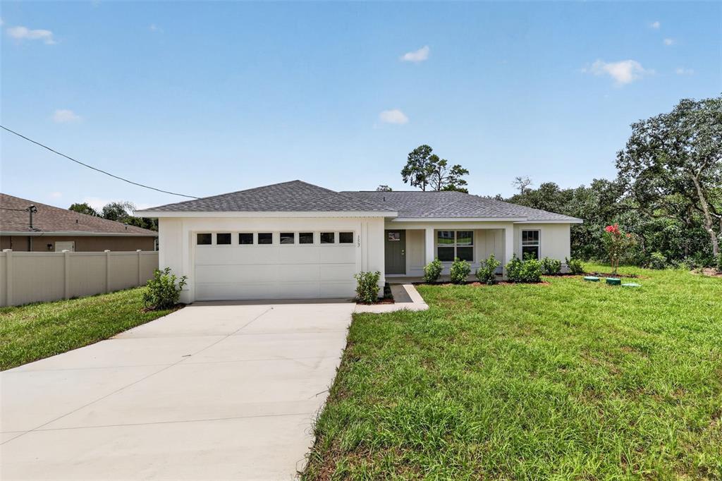 A single-story house with a white exterior, a two-car garage, and a concrete driveway — 103 WALNUT DRIVE, OCALA, FL
