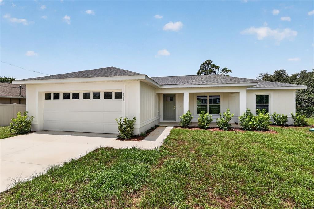A single-story house with a white exterior, a two-car garage, and a covered front porch — 103 WALNUT DRIVE, OCALA, FL