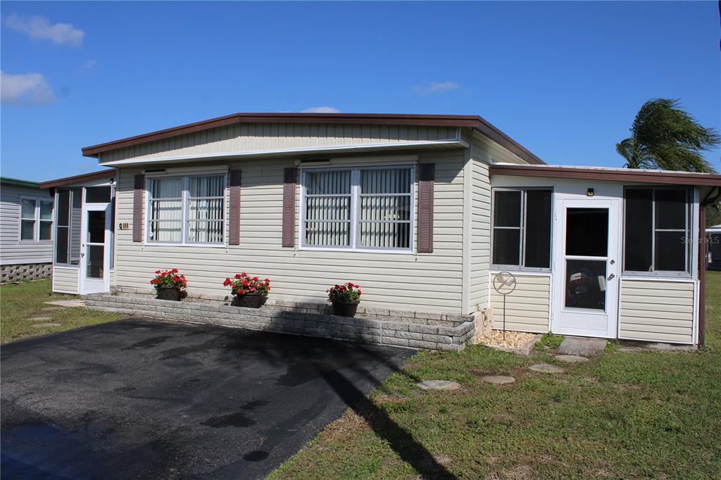 A single-story manufactured home with light siding, a paved driveway, and a small front porch — 5316 53RD AVENUE E UNIT Q111, BRADENTON, FL