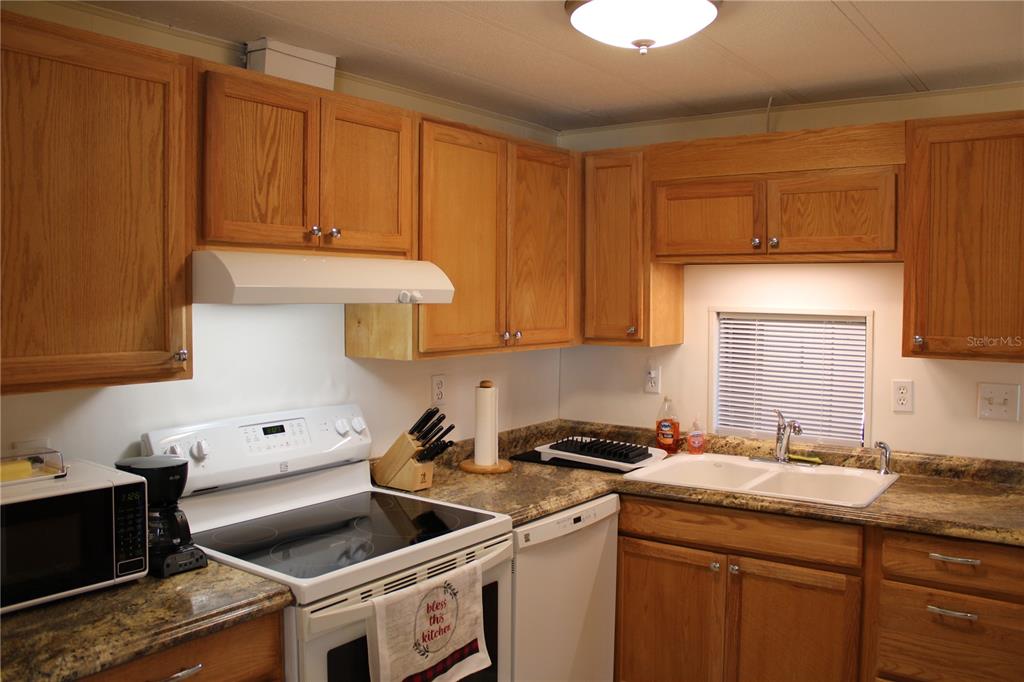 A kitchen features oak cabinets, laminate countertops, a white electric range, and a double sink — 5316 53RD AVENUE E UNIT Q111, BRADENTON, FL