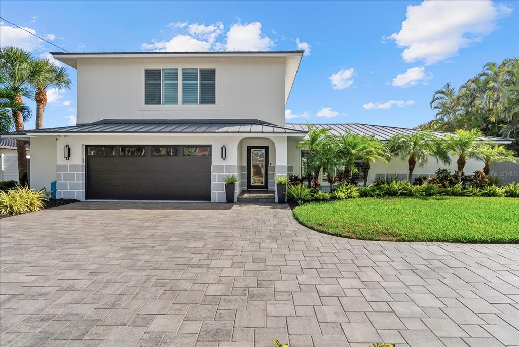A two-story house with a paved driveway, dark garage door, and metal roof — 813 IDLEWILD WAY, SARASOTA, FL