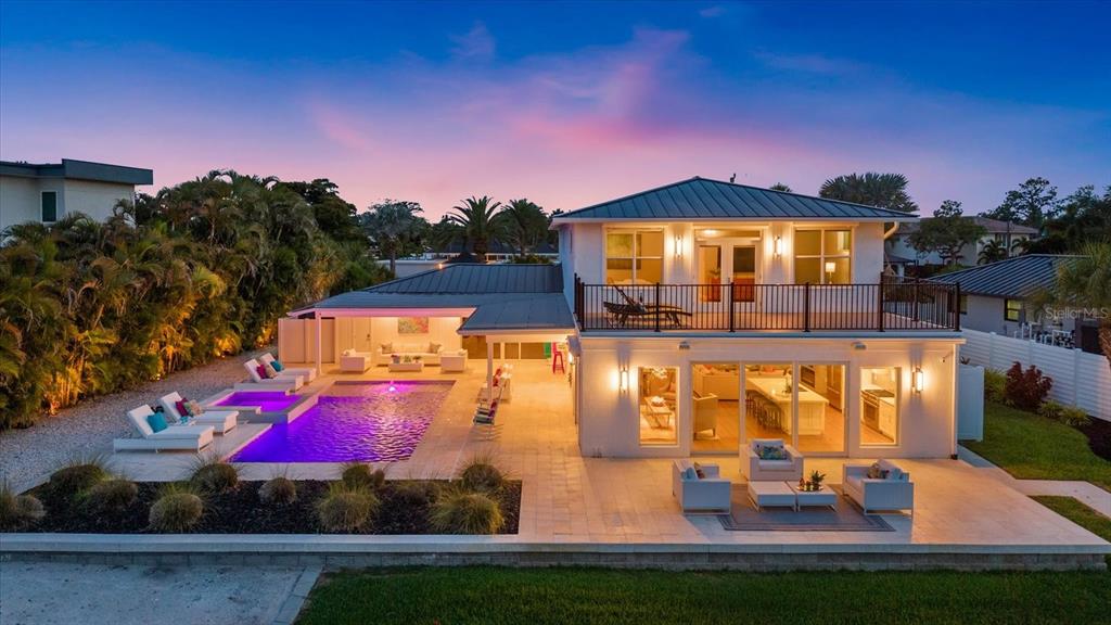 A two-story house with a pool, patio, and balcony at dusk — 813 IDLEWILD WAY, SARASOTA, FL