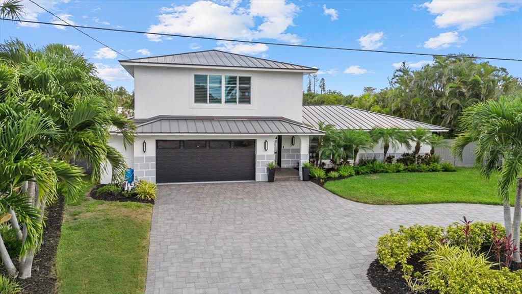 A two-story house with a metal roof, gray block-patterned siding, and a paved driveway — 813 IDLEWILD WAY, SARASOTA, FL