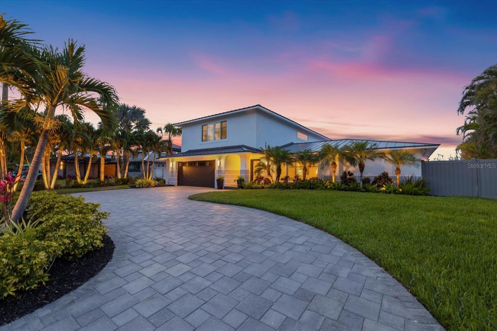 A two-story house with a paved driveway, palm trees, and a lawn at sunset — 813 IDLEWILD WAY, SARASOTA, FL