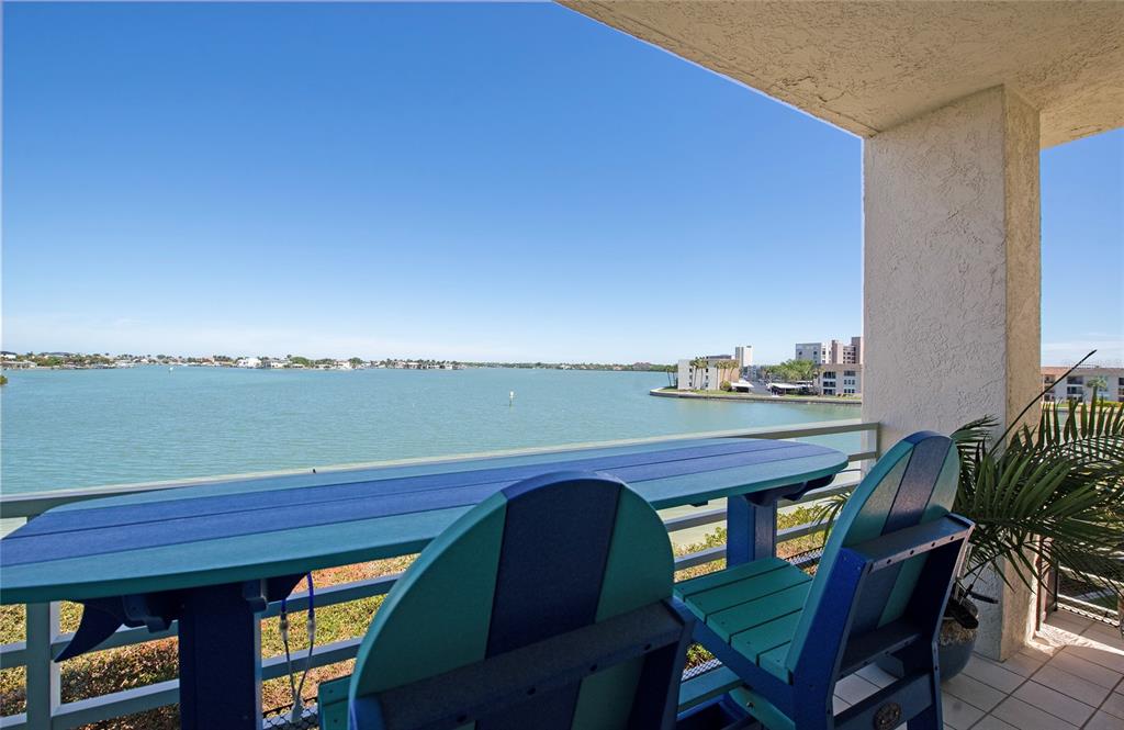 A balcony with a blue table and chairs overlooks a large body of water — 7979 SAILBOAT KEY BOULEVARD S UNIT 208, SOUTH PASADENA, FL