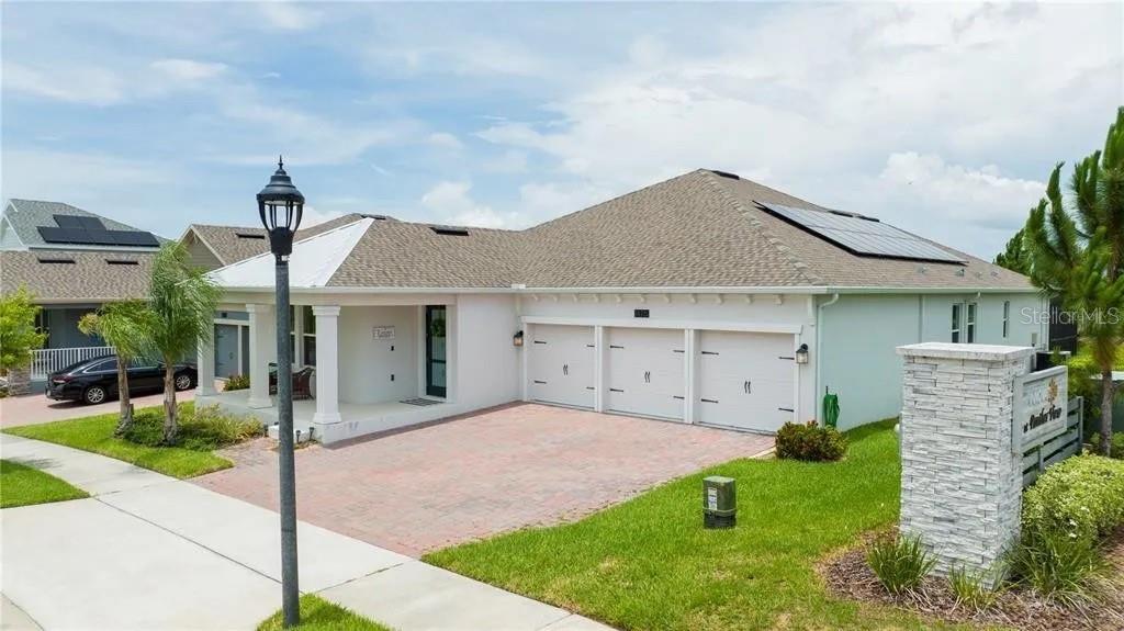 A single-story house with a three-car garage, a paved driveway, and solar panels on the roof — 14711 WINTER STAY DRIVE, WINTER GARDEN, FL