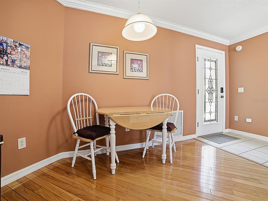 A dining area features a wooden drop-leaf table, two white chairs, and hardwood flooring — 7631 SE 170TH LONGVIEW LANE, THE VILLAGES, FL