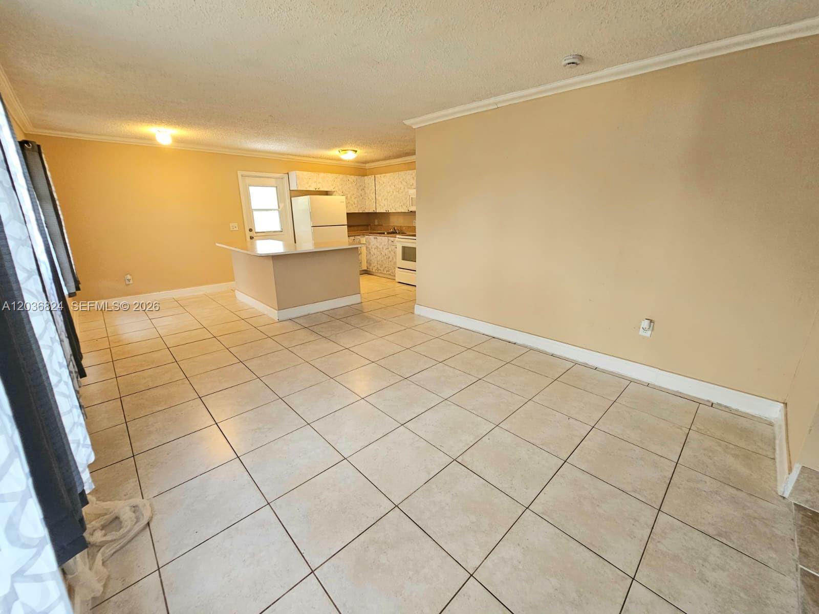 An open-concept kitchen with a breakfast bar and tiled floors overlooks a living area — 649 NW 19th St, Pompano Beach FL 33060, POMPANO BEACH, FL
