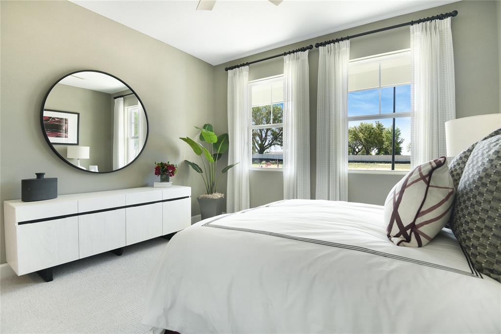 A bedroom features a white dresser, a round mirror, a potted plant, and two windows — 10152 TURNBERRY LANE, LEESBURG, FL