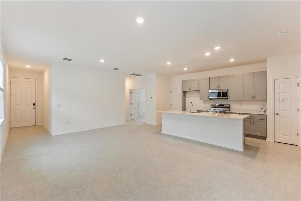 An open-concept kitchen and living area features light gray cabinets, a white island, and tile flooring — 1202 ATLANTIC AVENUE, FRUITLAND PARK, FL