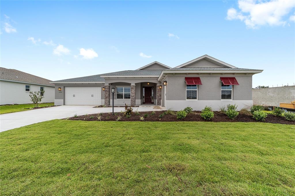 A single-story house with a gray exterior, stone accents, and red window awnings — 10305 SW 105TH TERRACE, OCALA, FL