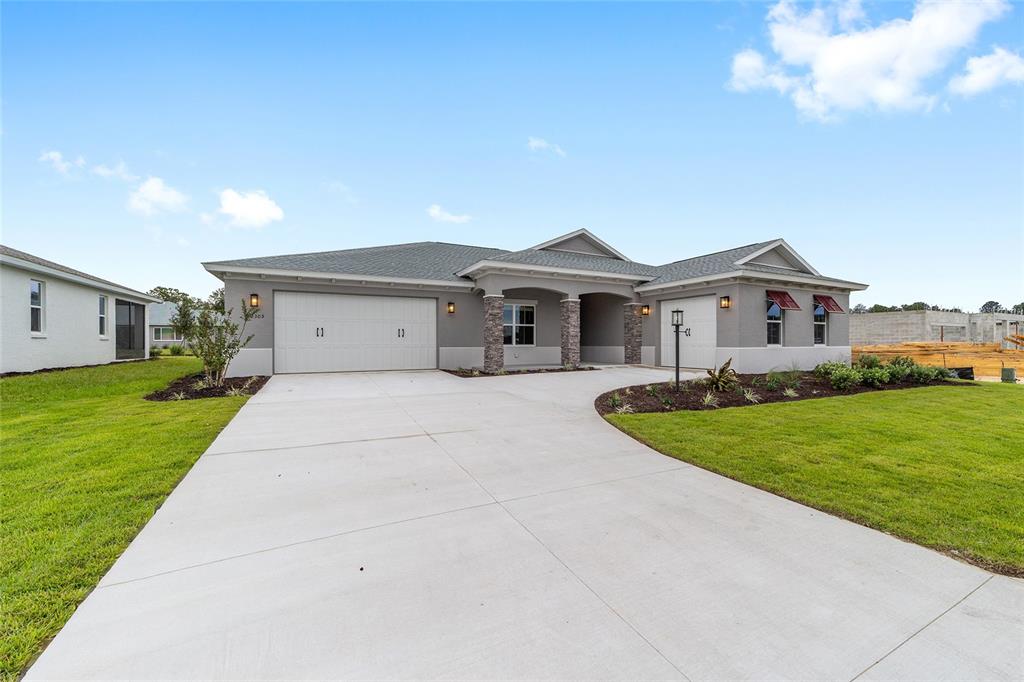 A single-story house with a gray stucco exterior, stone accents, and a concrete driveway — 10305 SW 105TH TERRACE, OCALA, FL