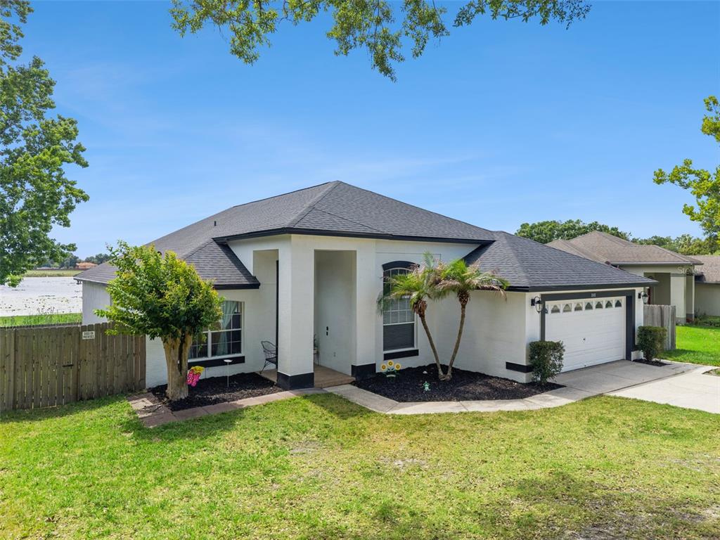A single-story white house with a dark roof, a two-car garage, and a fenced yard — 808 LAKE JACKSON CIRCLE, APOPKA, FL