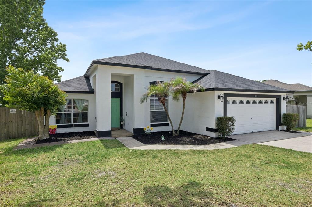 A single-story house with white stucco walls, a dark roof, and a green front door — 808 LAKE JACKSON CIRCLE, APOPKA, FL