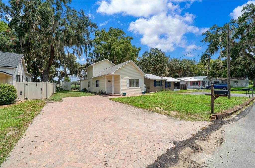 A light yellow house with a paved driveway sits on a grassy lot with trees — 506 LAKE STREET, INVERNESS, FL