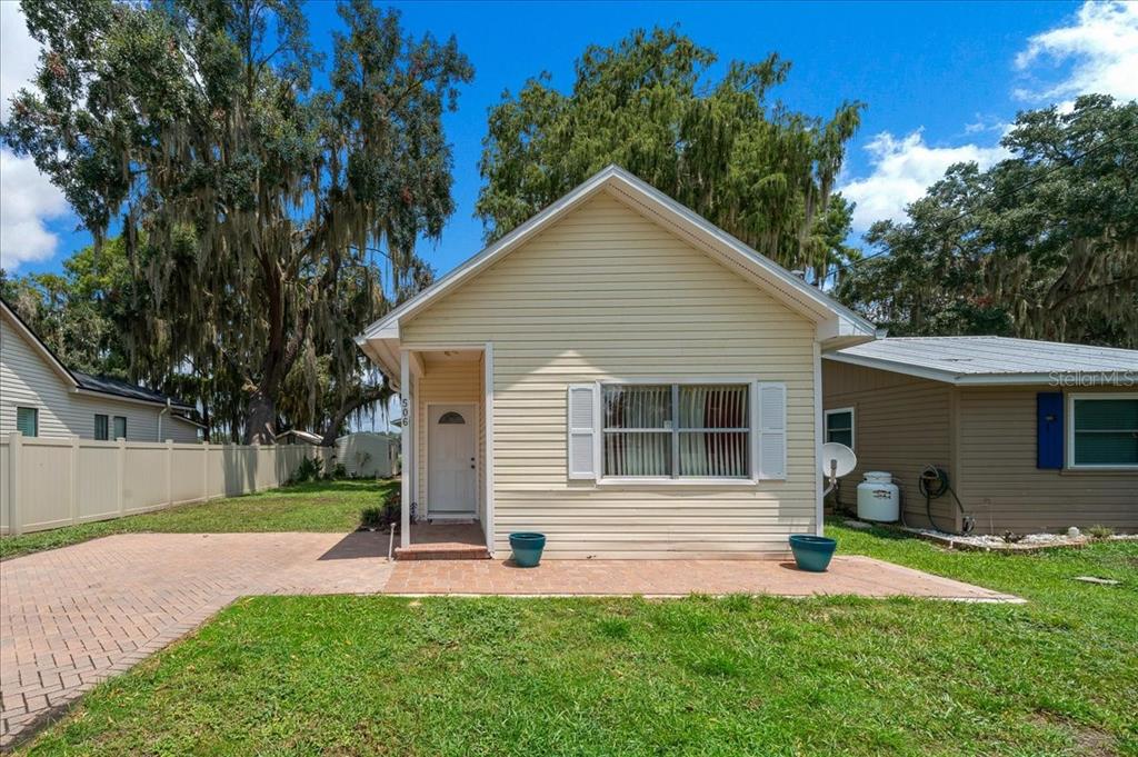 A single-story house with light yellow siding, a brick patio, and a white front door — 506 LAKE STREET, INVERNESS, FL