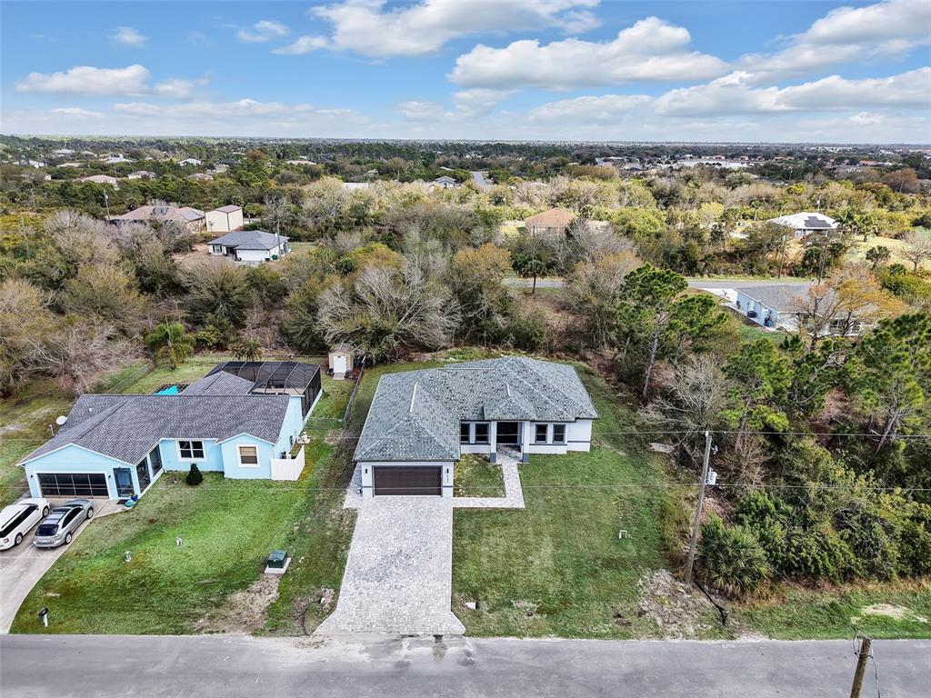 An aerial view shows two suburban houses with paved driveways surrounded by trees and vegetation — 6192 KAMBACH STREET, PORT CHARLOTTE, FL