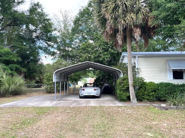 A white car is parked under a metal carport next to a light-colored house — 1569 NW 109TH AVENUE, OCALA, FL