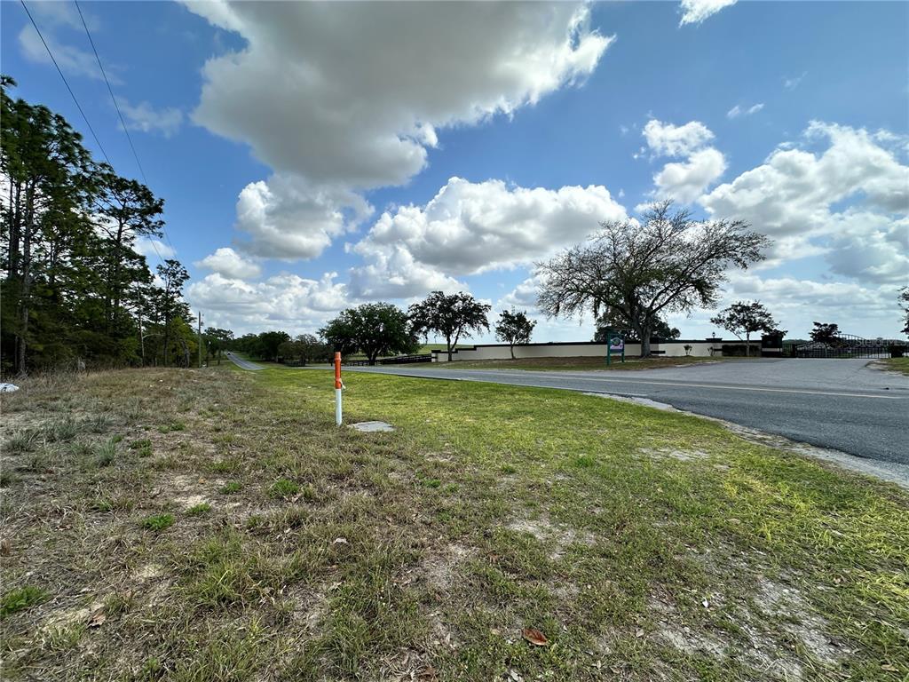 A grassy roadside lot features a survey marker and a view of distant trees — TBD SE 30TH STREET, MORRISTON, FL