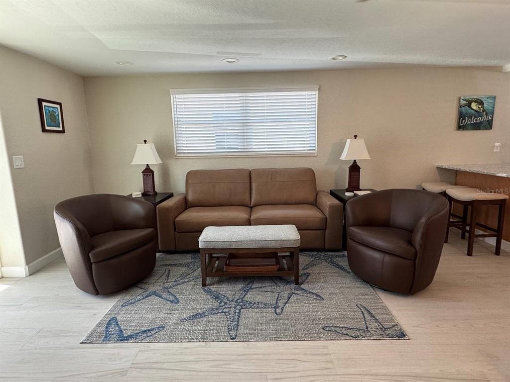 A living room features a brown sofa, two armchairs, and a starfish-patterned area rug — 6154 MIDNIGHT PASS ROAD UNIT C15, SARASOTA, FL