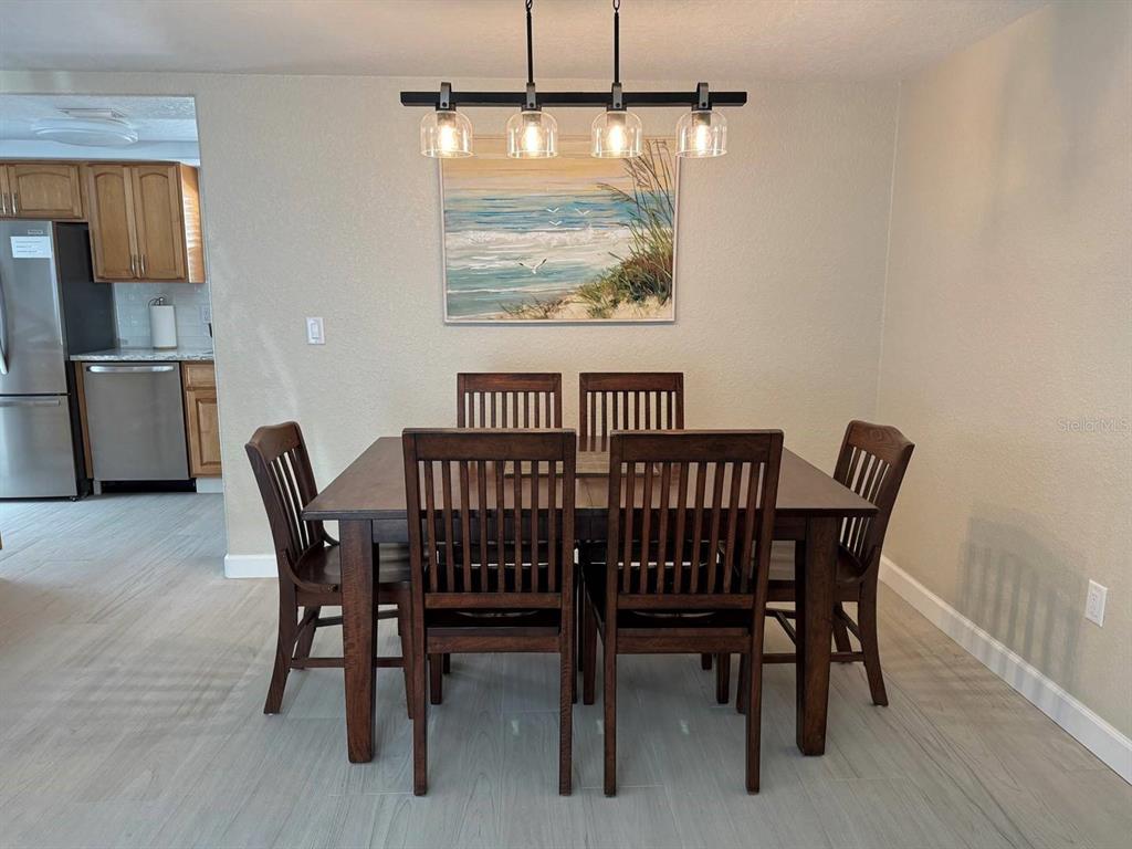A dining room features a dark wood table with six chairs beneath a linear pendant light — 6154 MIDNIGHT PASS ROAD UNIT C15, SARASOTA, FL