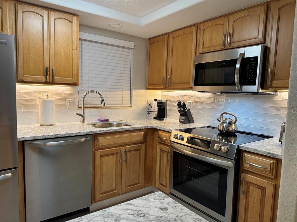 A kitchen with wood cabinets, stainless steel appliances, and white subway tile backsplash — 6154 MIDNIGHT PASS ROAD UNIT C15, SARASOTA, FL